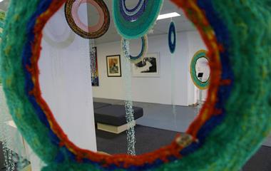 A piece of art made from netting material hanging in a gallery.