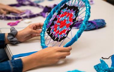 A child creating a dream catcher with blue and purple colours.