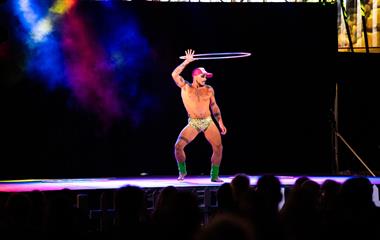 A male artist performing on stage with a hoola hoop.