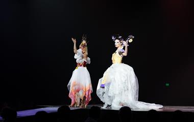 Two female models wearing colourful dresses on stage.