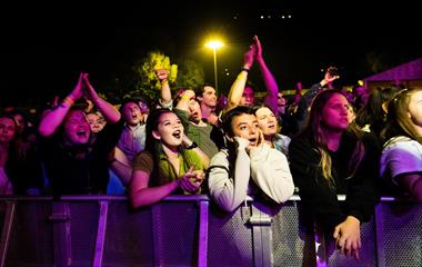 A standing crowd singing at a music festival.