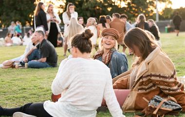 A group of people sitting on the grass at a music festival.
