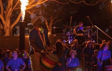 A man playing a drum to a crowd.