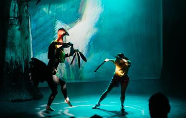 Two artists performing on stage wearing costumes.