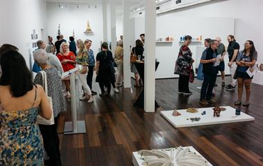 A group of people admiring artwork in a gallery.
