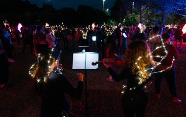 A crowd of performers playing musical instruments to an audience.