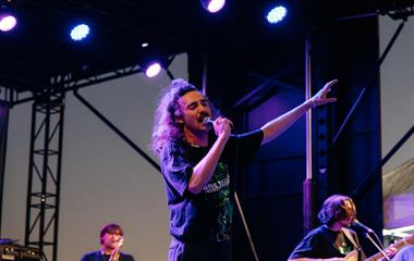A male artist singing into a microphone on stage.