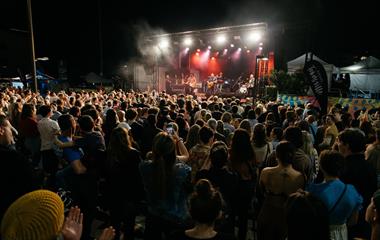 Three artists on stage performing to a crowd.