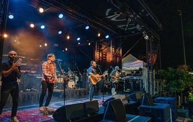 Four artists on stage with microphones and guitars.