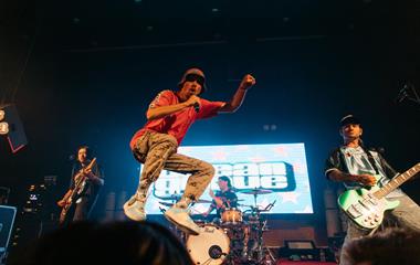 A male artist jumping in the air while holding a microphone.