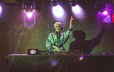 A DJ using a turntable on stage wearing headphones.