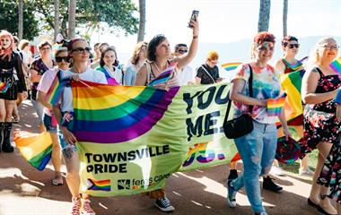 A group of people wearing colourful clothes holding a banner.