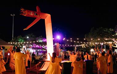A group of people wearing yellow coats facing a dancing inflatable.