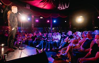 A male speaking into a microphone to an audience.