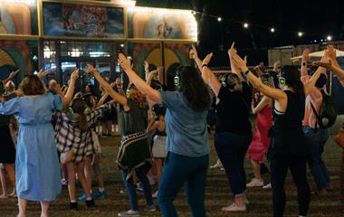 A group of people with their arms in the air wearing headphones.