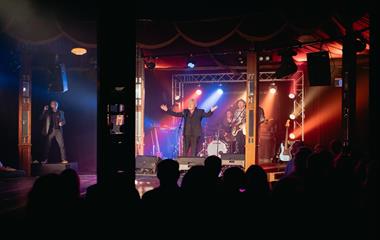 A male singer performing with a band on stage.